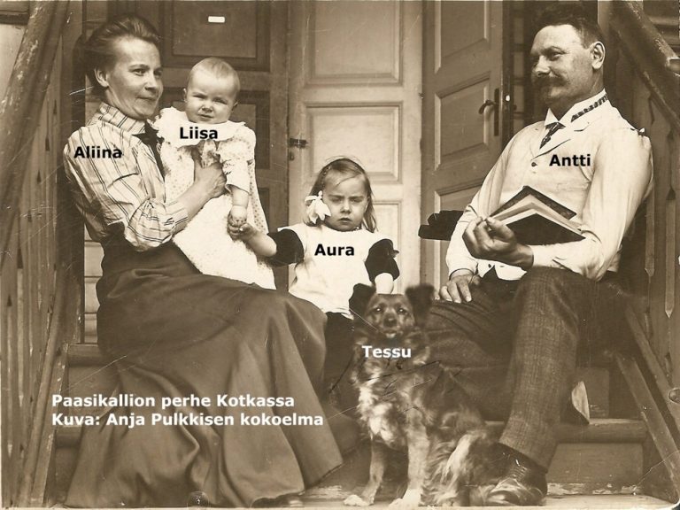 Mustavalkovalokuva, missä Aliina ja Antti Paasikallio istuvat ulkorappusilla lapsiensa Liisan ja Auran sekä Tessu-koiran kanssa Kotkassa.