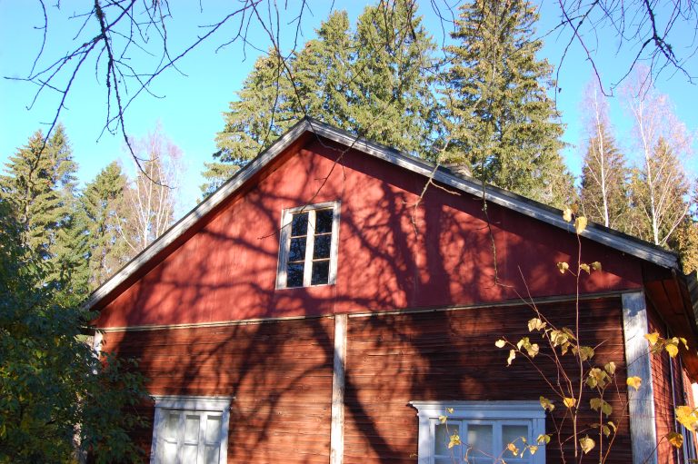 Hirsirakennuksen pääty, joka on punaiseksi maalattu – päätykolmiossa on eri punaisen sävy.