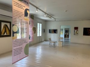 Pääasiassa ripustettavaa taidetta näyttelytilassa, jonka seinät ja lattia on maalattu vaaleaksi.
