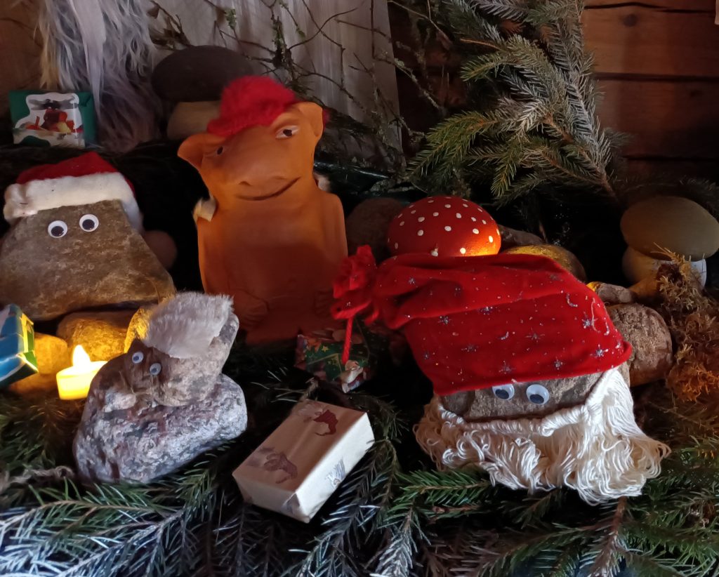 Kivistä tehtyjä tonttuhahmoja, joiden alla on kuusenhavuja.