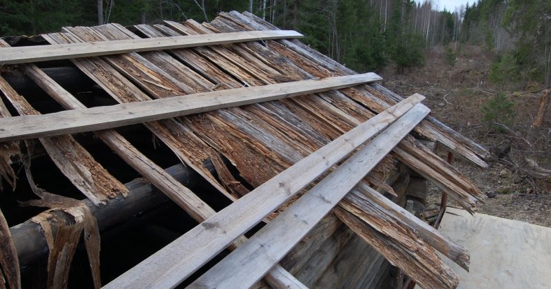 Hirsirakennuksen laho lautakatto sekä poikittaiset ruoteet, joihin pressu oli kiinnitetty.