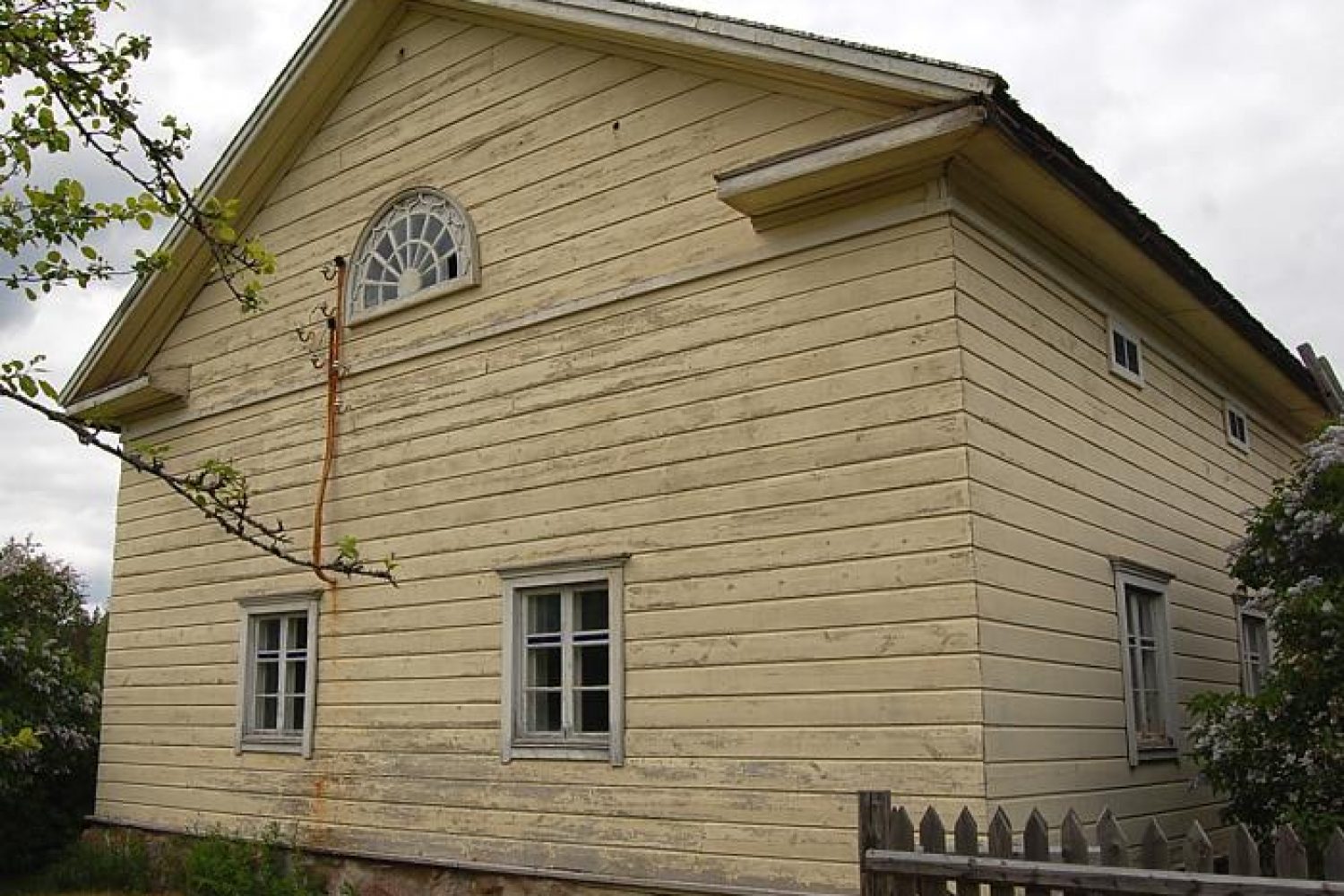 Kuvassa Lyytikkälän tilan päärakennuksen vaakavuorattua ja vaaleaksi maalattua päätyä ruutuikkunoineen. Päätykolmiossa sijaitsevat kissanpenkit ja hämähäkkiverkkoa muistuttava lunetti-ikkuna.