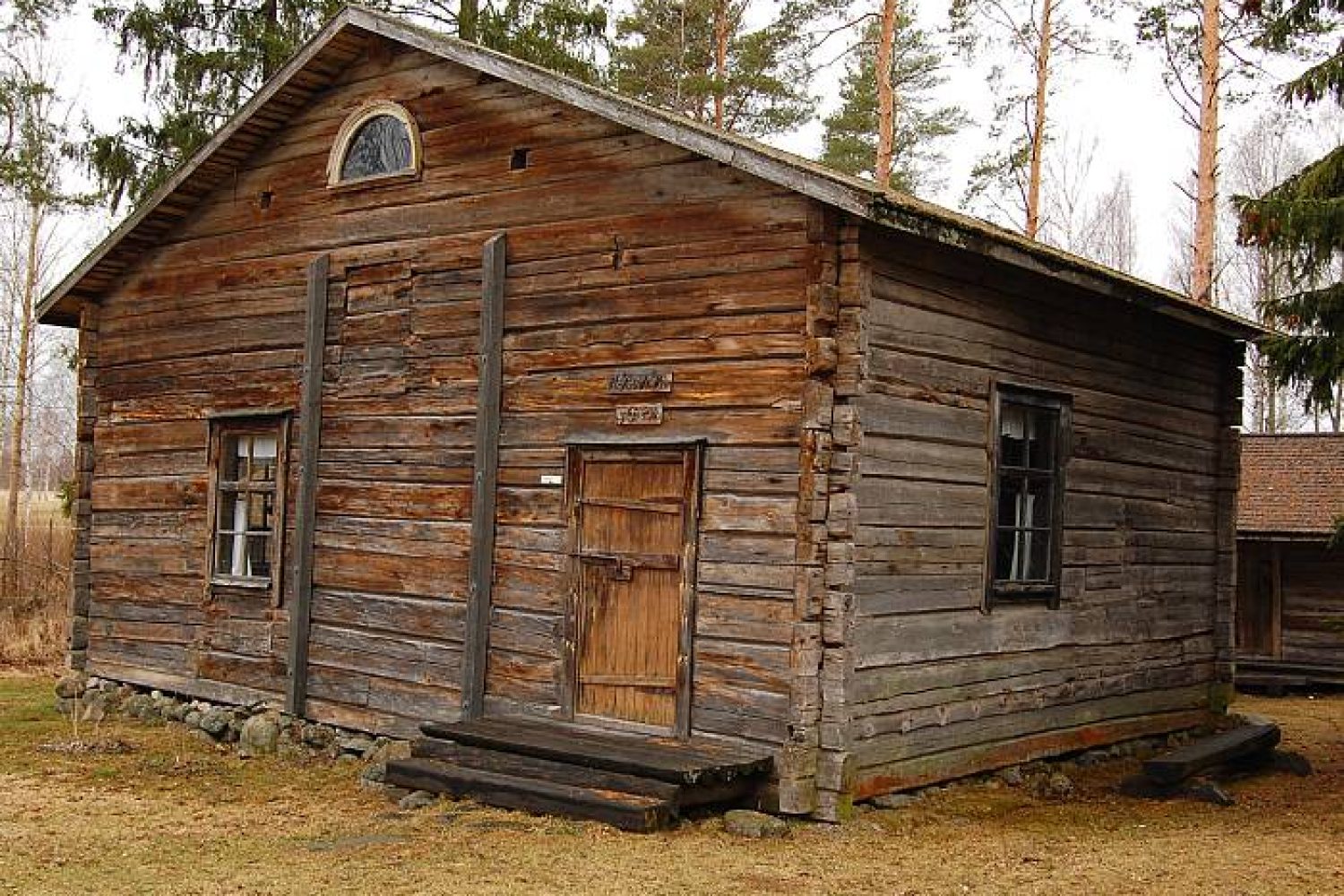 Syksyllä otettu kuva, jossa näkyy museon päärakennus: ladotulle luonnonkivijalalle pystytetty pitkänurkkainen hirsirakennus, jonka etupäätyä on tuettu kahdella tukipiirulla eli völjärillä.