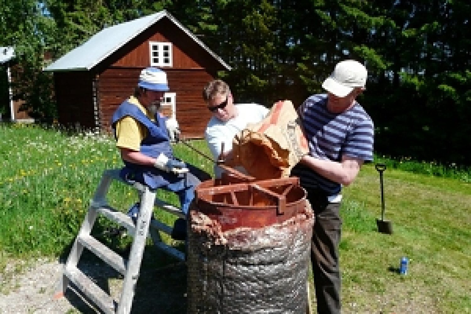 Kaksi miestä kaataa tynnyriin punamultaa ja kolmas mies istuu pukilla sekoittamassa.