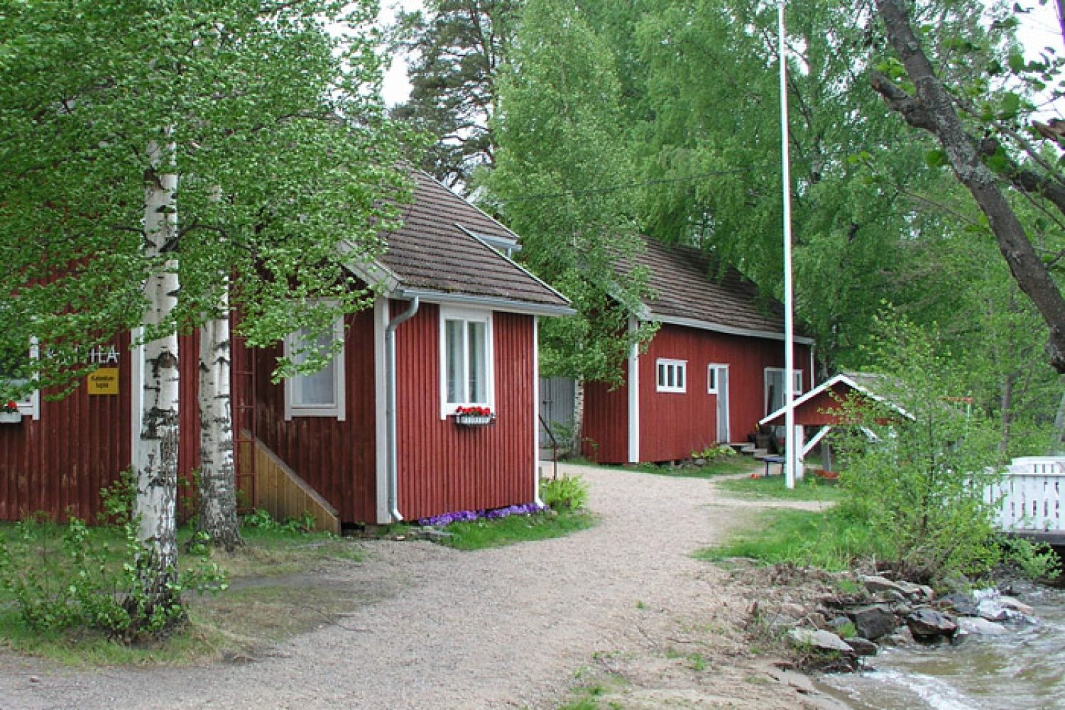 Ulkokuva kesältä Miekankosken saumarimavuoratusta, ja punaiseksi maalatusta kahvilasta ja museosta.