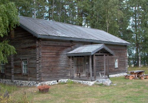 Tukkilaistupa on maalaamaton pitkänurkkainen hirsirakennus, jossa on lomalautakatto.