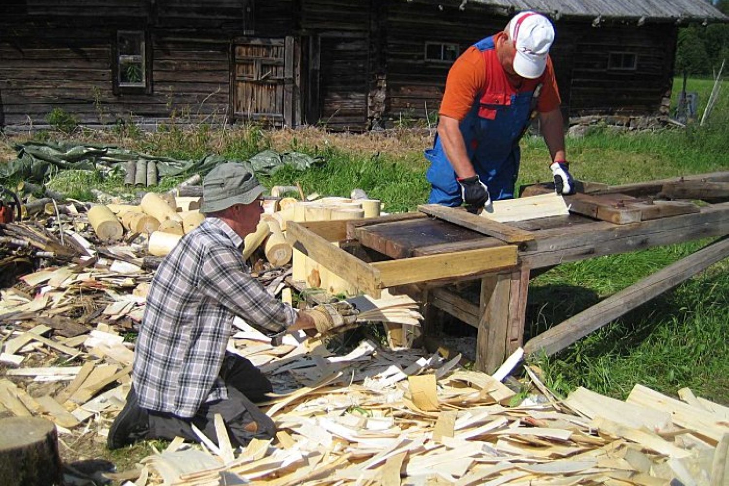 Höyläri ja koppari höyläämässä kattopäreitä Pitkäpallon pihalla haapapölleistä.